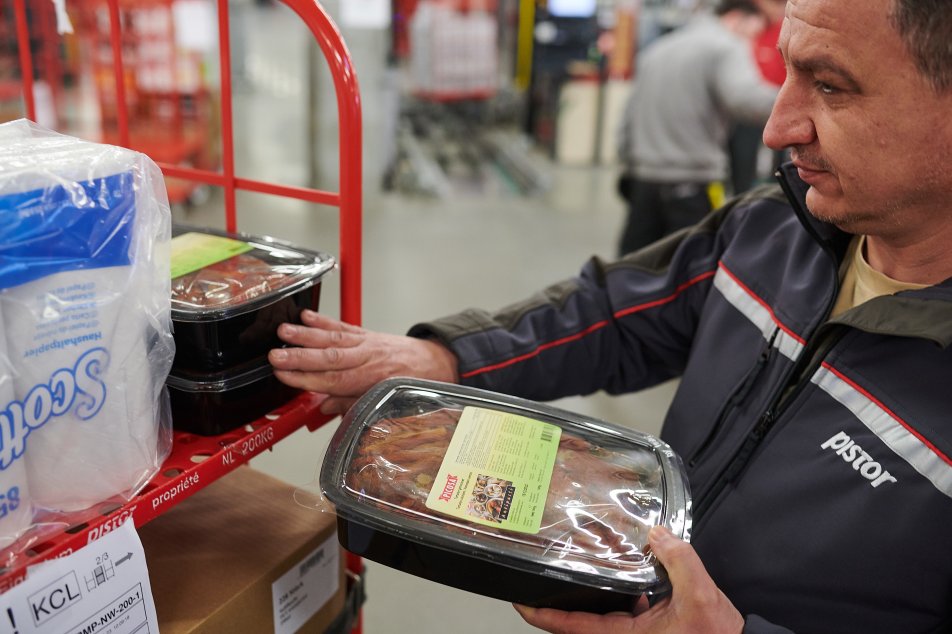 Pistor Mitarbeitender Besim Zeqiri verdichtet die Produkte auf dem roten Rollbehälter